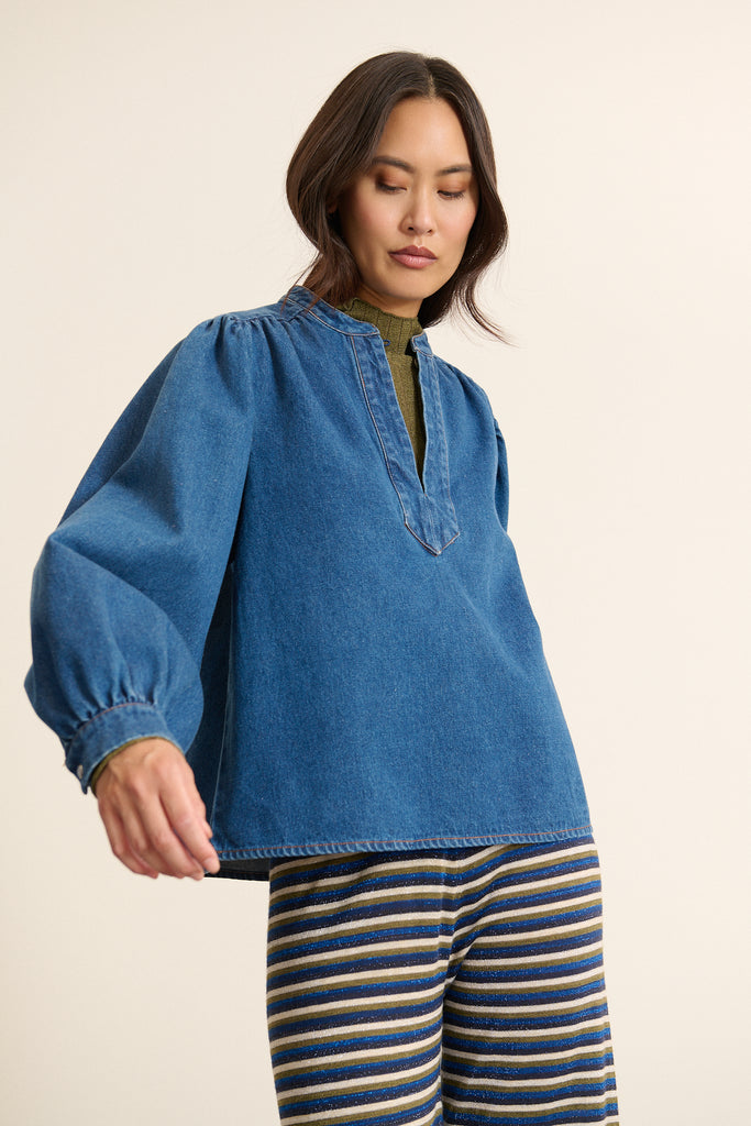 Tissu 100 %  coton, en denim léger, coloris bleu moyen au toucher souple et au tombé fluide  sur l'ensemble de la blouse. 