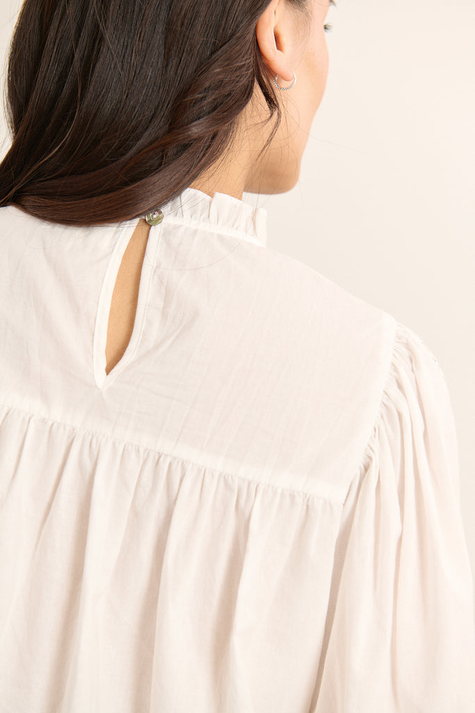 Vue arrière de la blouse ample, volume souple avec fronces sous l'empiècement et finition arrondie en bas.