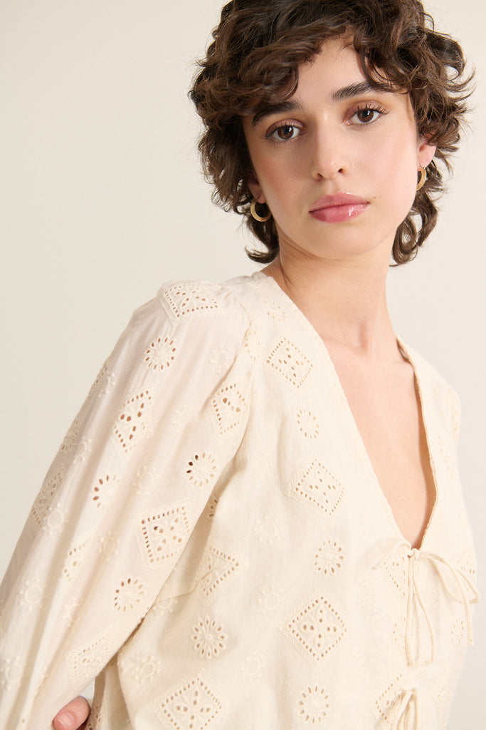 Blouse fabriquée entièrement en coton, coloris écru, fermeture à nœud et manches longues. 