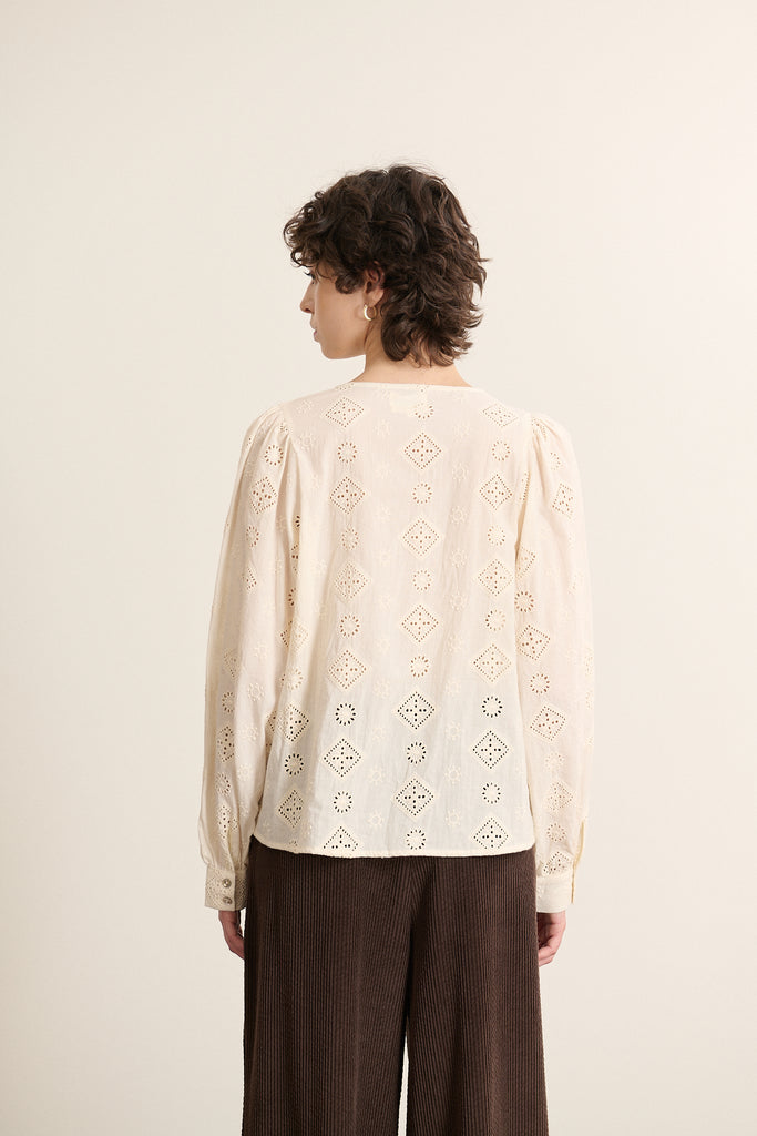 Col fendu sur le devant, fermé par un nœud, apparant une touche délicate à cette pièce en broderie anglaise écrue.