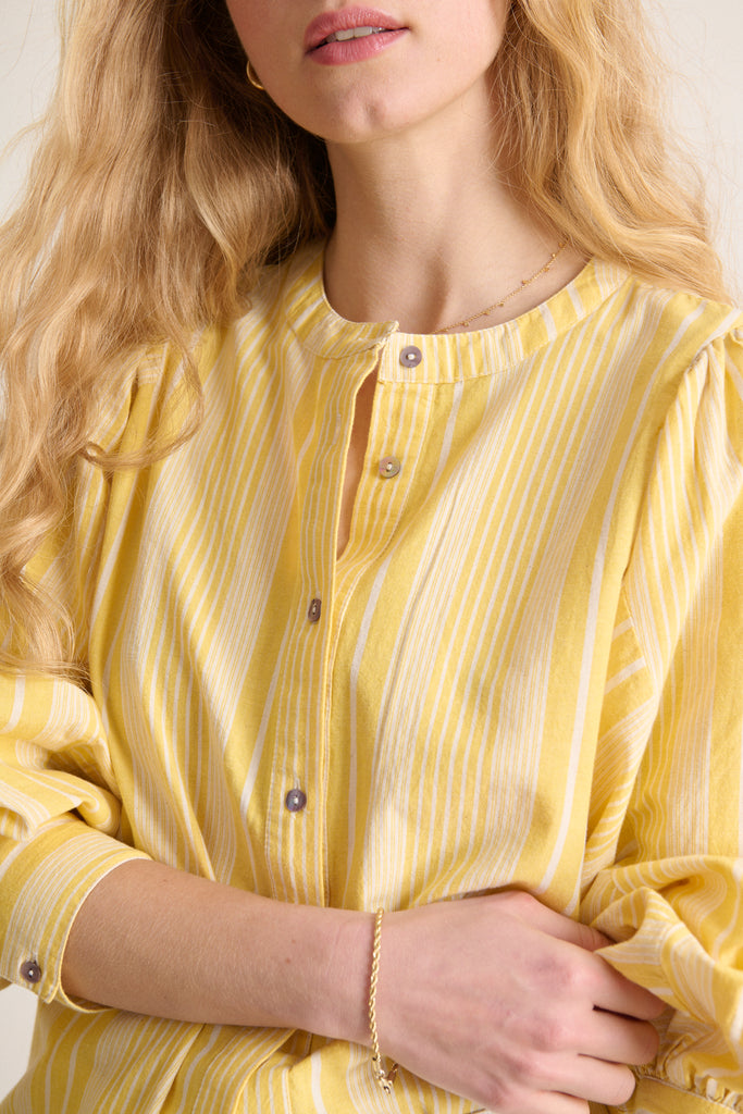Haut en coton jaune et blanc avec col rond manches larges et fermeture boutonnée à l'avant 