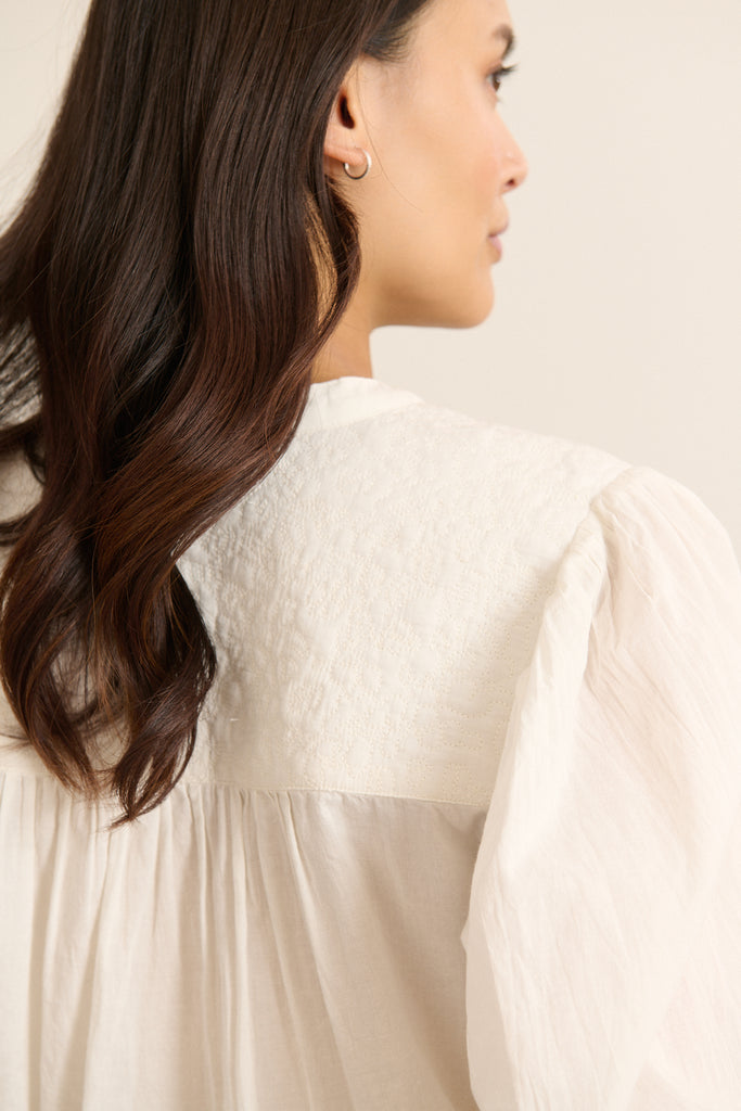 Blouse pour femme coloris blanc aux manches longues, à la coupe ample et aux découpe à l'avant.