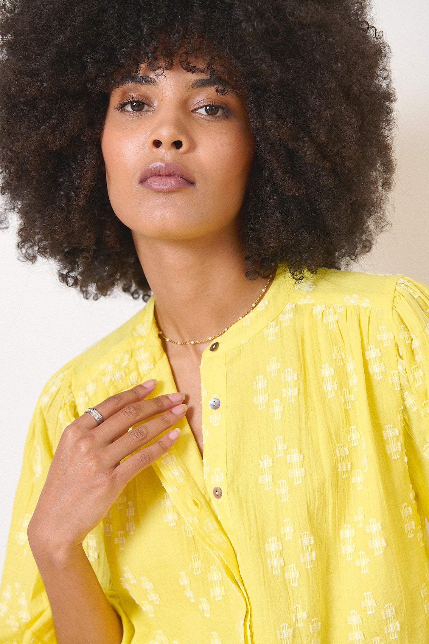 Blouse jaune en broderie plumetis, manches amples boutonnées, détails froncés et découpes élégantes