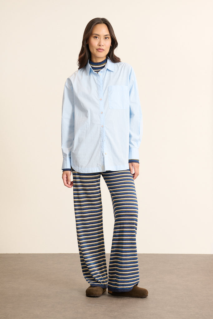 Mannequin femme de face portant une chemise ample bleu en coton, col classique, poche poitrine et coupe fluide. 