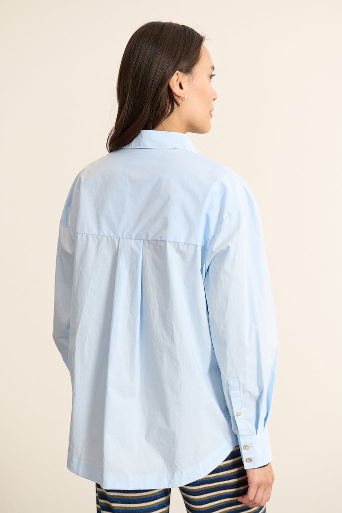Vue arrière de la chemise ample, découpe horizontale haute avec fronces légères pour créer du volume au dos. 