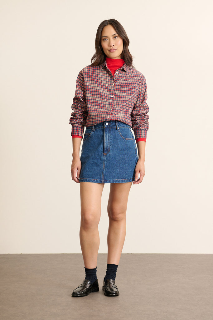 Mannequin femme de face portant une chemise rouge à carreaux, coupe ajustée avec col classique et poche poitrine.