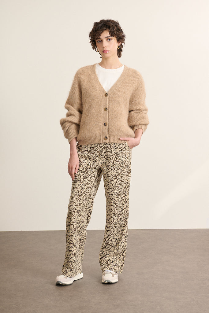 Mannequin femme de face portant un gilet ample beige, col V profond, manches longues et fermeture par boutons effet corne.
