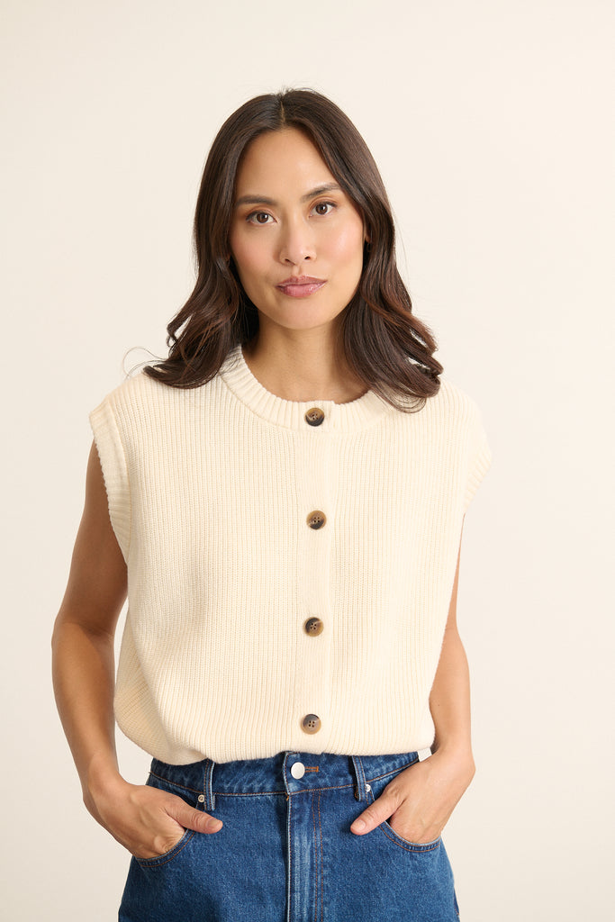 Mannequin femme de face portant un gilet sans manches écru, coupe droite avec encolure ronde et fermeture boutonnée.