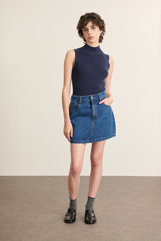 Mannequin femme de face portant un pull sans manches marine, coupe ajustée avec col montant et finitions bord-côtes.