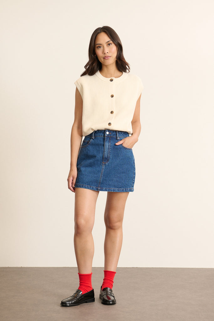 Mannequin femme de face portant une mini jupe en denim bleu, coupe droite avec ceinture plate et poches plaquées devant.