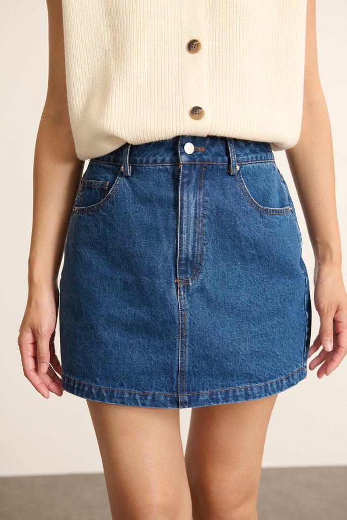 Mini jupe en denim bleu 100 % coton, collection Garance Paris automne hiver 2025, poches devant et dos, zip et bouton.