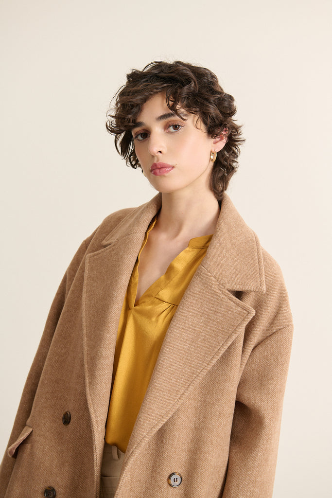Gros plan sur la poche à rabat du manteau TRAVIS coloris beige, élégante par son bouton effet corne.