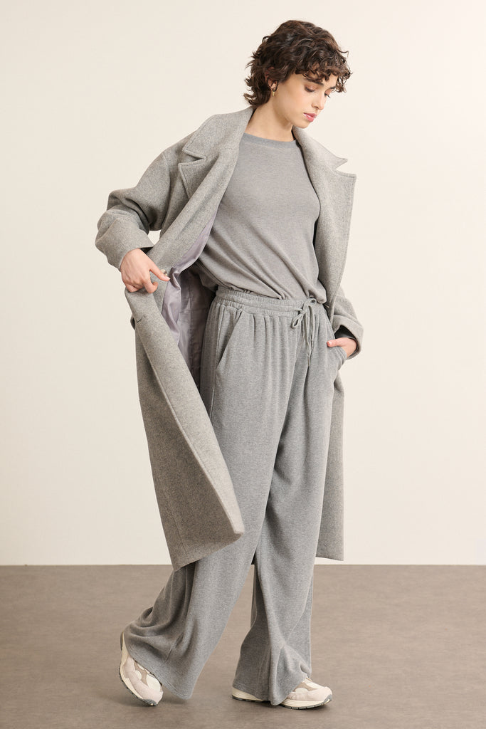 Détail d'une manche du manteau long Garance Paris coloris gris avec bouton effet corne et poches à rabats.