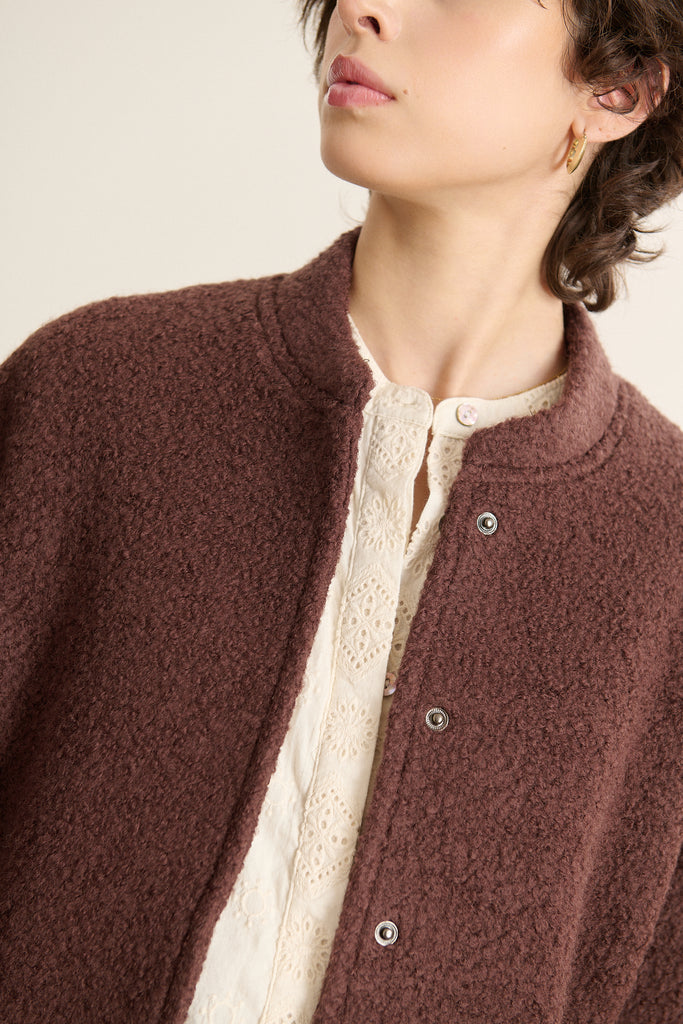 Mannequin femme de face portant un manteau court esprit bombers, coupe droite avec col rond et emmanchures descendues.