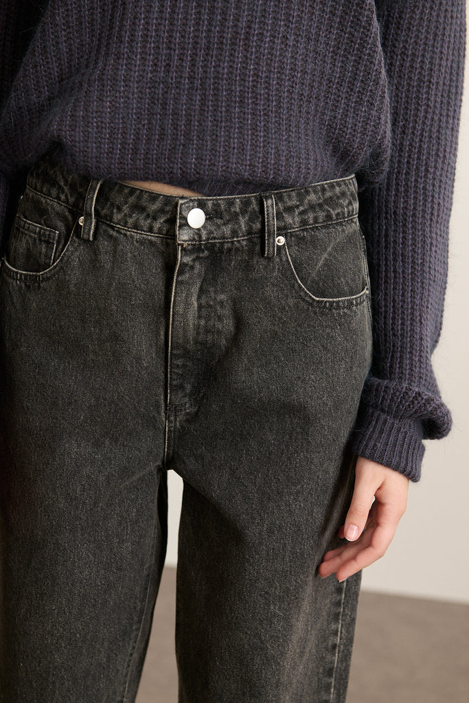 Fermeture par zip métallique et bouton, placés sur une ceinture droite avec passants larges et finitions renforcées.