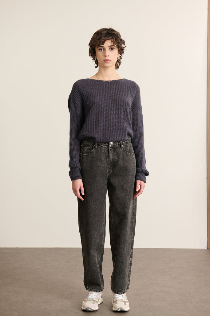 Mannequin femme de face portant un jean coupe ballon coloris gris, taille haute et volume arrondi sur la jambe.