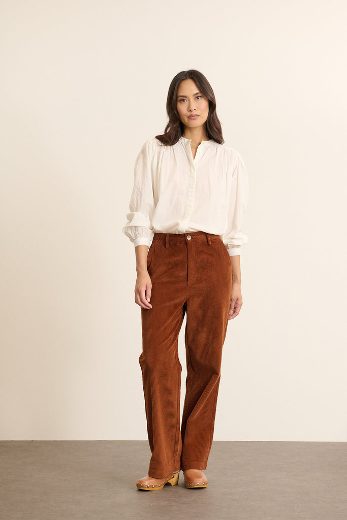 Mannequin femme de face portant une blouse ample coloris blanc en voile de coton, découpe matelassée sur le devant.