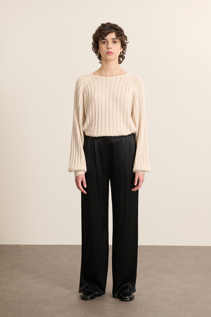 Mannequin femme de face portant un pull beige à côtes, col rond, manches ballon et emmanchures raglan pour un volume structuré