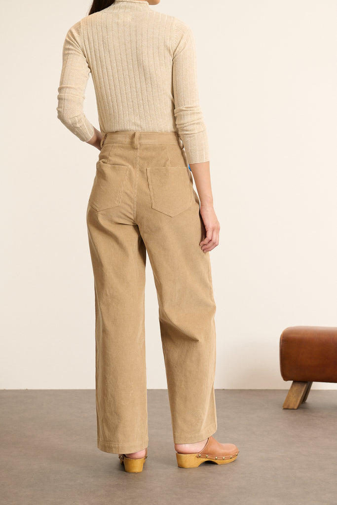 Femme portant un pantalon coloris beige Garance Paris à la coupe droite et aux poches plaquées devant et derrière.