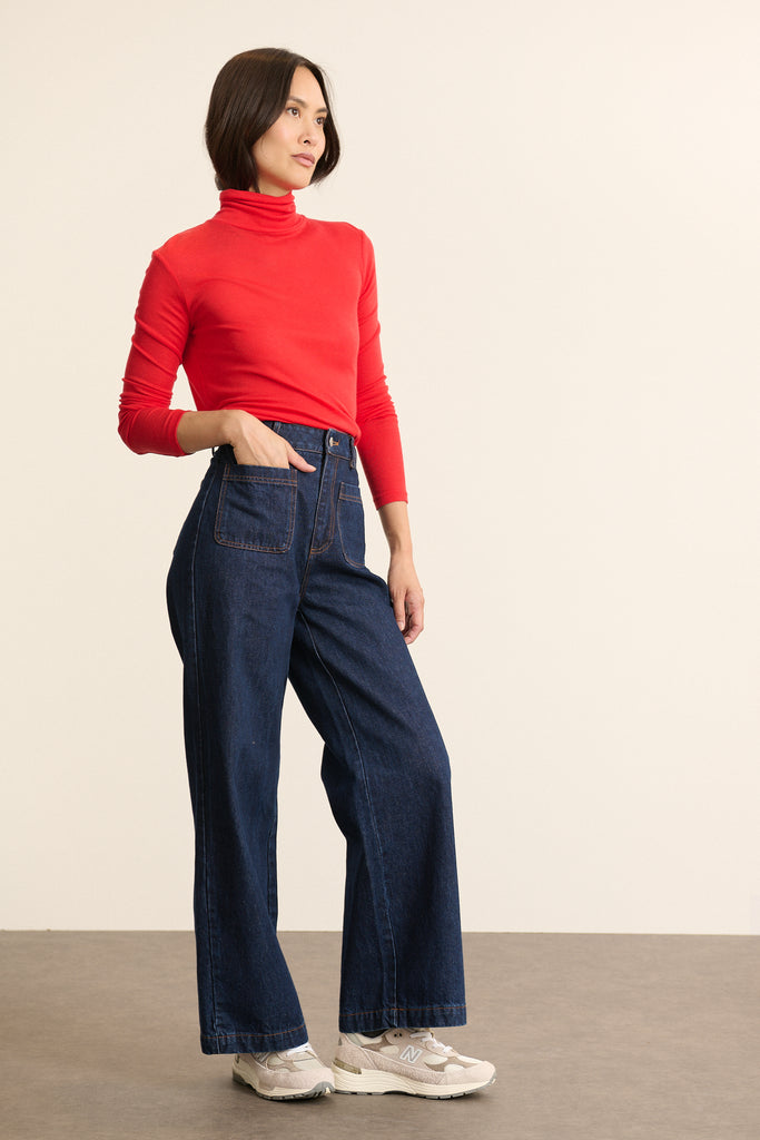 Femme portant le pantalon TORRES en denim coloris brut à la coupe longue et droite, avec fermeture zippée et bouton.