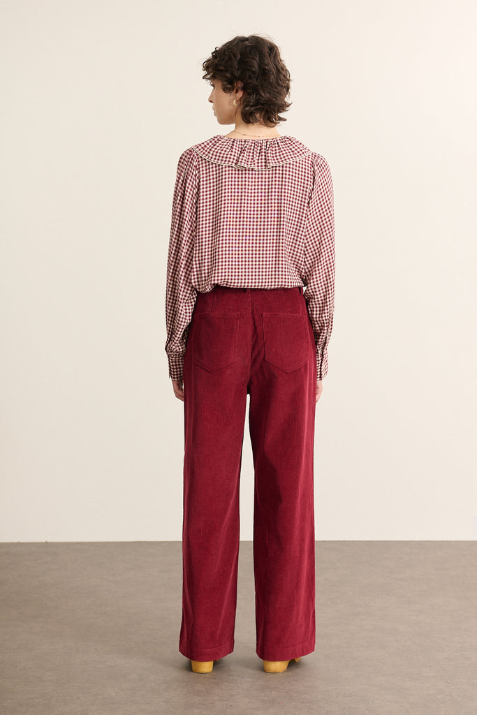 Vue arrière de la blouse à col volanté, col visible sur le dos, coupe droite avec couture centrale et base arrondie.