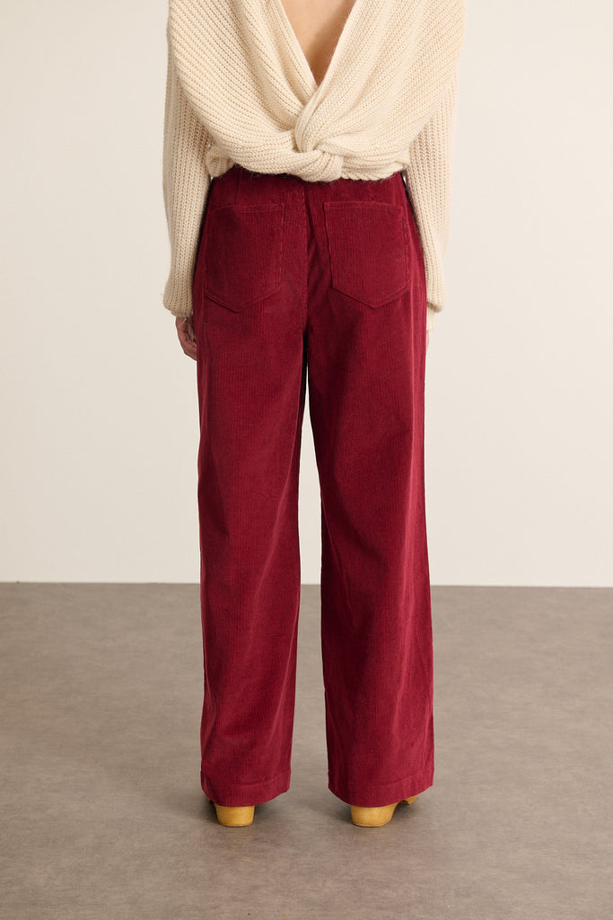 Bas pour femme avec poches à l'avant et à l'arrière, fermé par une fermeture zip et un bouton, coloris grenat.