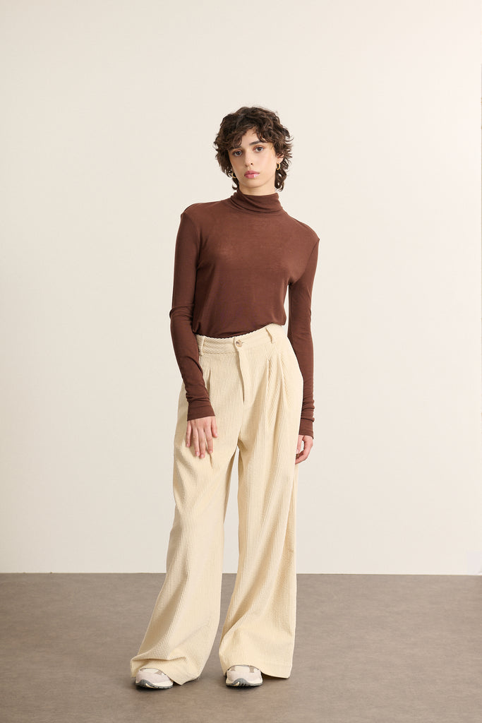 Mannequin femme de face portant un sous-pull marron à col montant, coupe ajustée et manches longues en maille fine. 