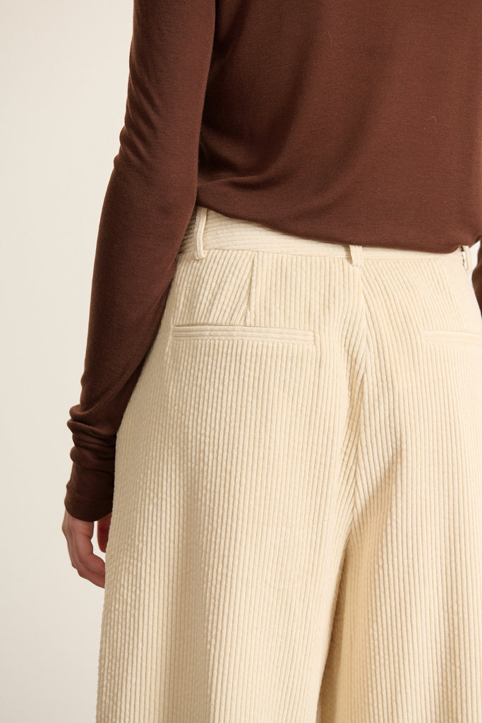 Tee-shirt aux manches longues avec tête de manche montée et coupe près du bras, finitions simples sans poignets.