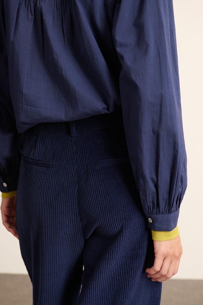 Velours 100% coton à côtes fines, coloris marine, toucher doux et tombé fluide sur une coupe large à jambe structurée.