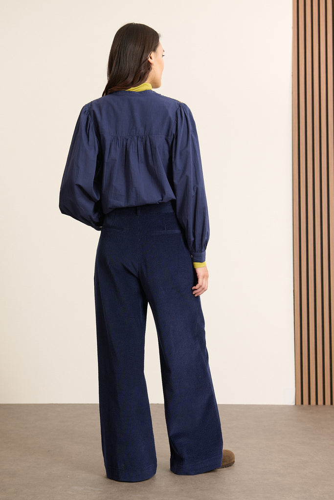 Vue arrière du pantalon en velours, coupe droite avec dos lisse, ceinture structurée et finitions nettes en bas de la jambe.