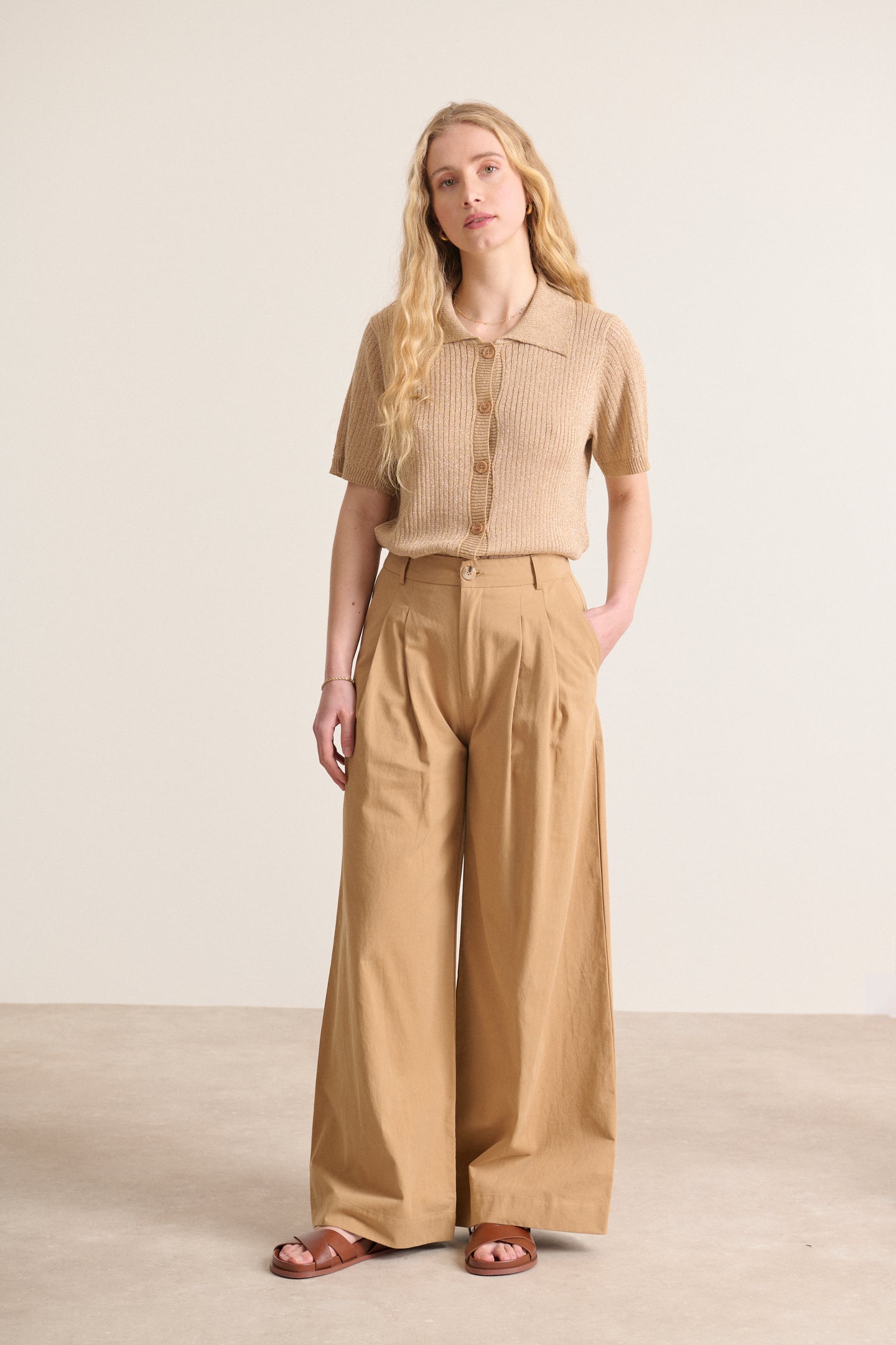 Pantalon élégant  au coloris beige avec jambes larges et taille haute avec passants détails de plis à l'avant 