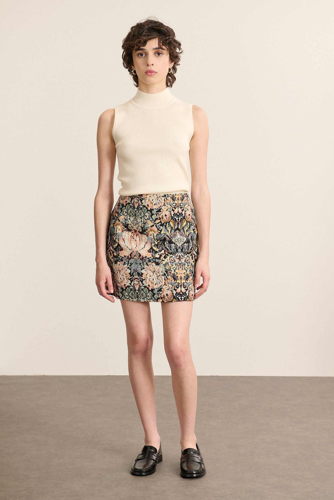Mannequin femme de face portant un pull sans manches écru, coupe ajustée avec col montant et finitions bord-côtes.