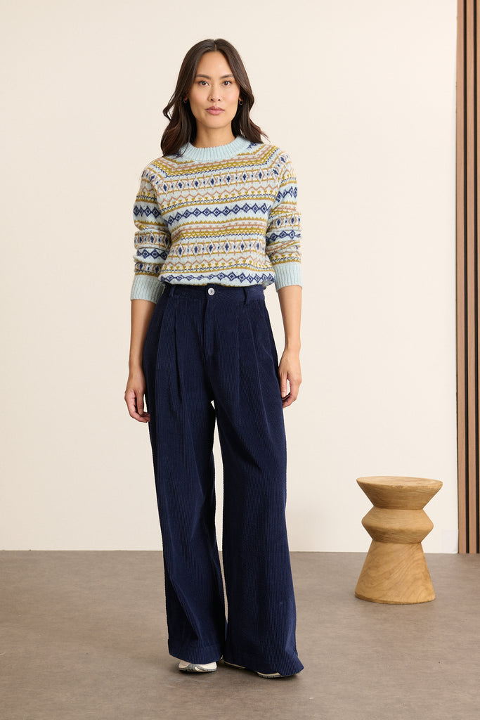 Mannequin femme de face portant un pull bleu en maille jacquard, motif esprit norvégien placé sur le haut du buste et des manches.