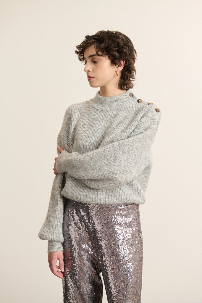 Pull ample gris avec bouton d’épaule, collection Garance Paris automne hiver 2025, maille chaude et détails soignés.