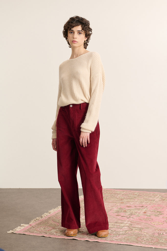 Mannequin femme de face portant un pull beige à manches longues, coupe droite avec col rond devant et décolleté au dos.