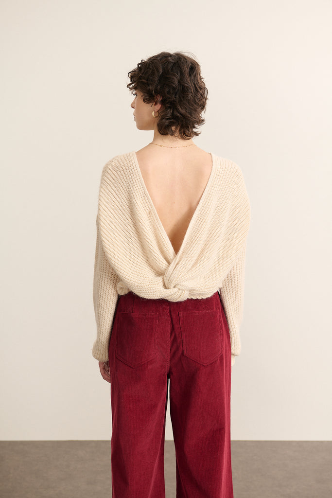 Vue arrière du pull beige, décolleté profond en V orné d’un nœud fixe et coupe droite légèrement ajustée.