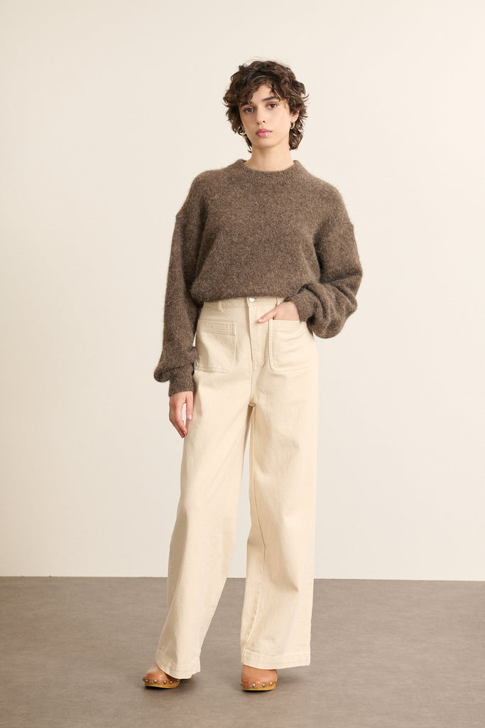 Mannequin femme de face portant un pull marron à encolure ronde, coupe ample au buste et resserrée à la taille.