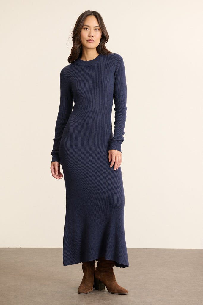 Mannequin femme de face portant une robe longue en maille marine, cintrée à la taille et évasée dans le bas avec col rond.
