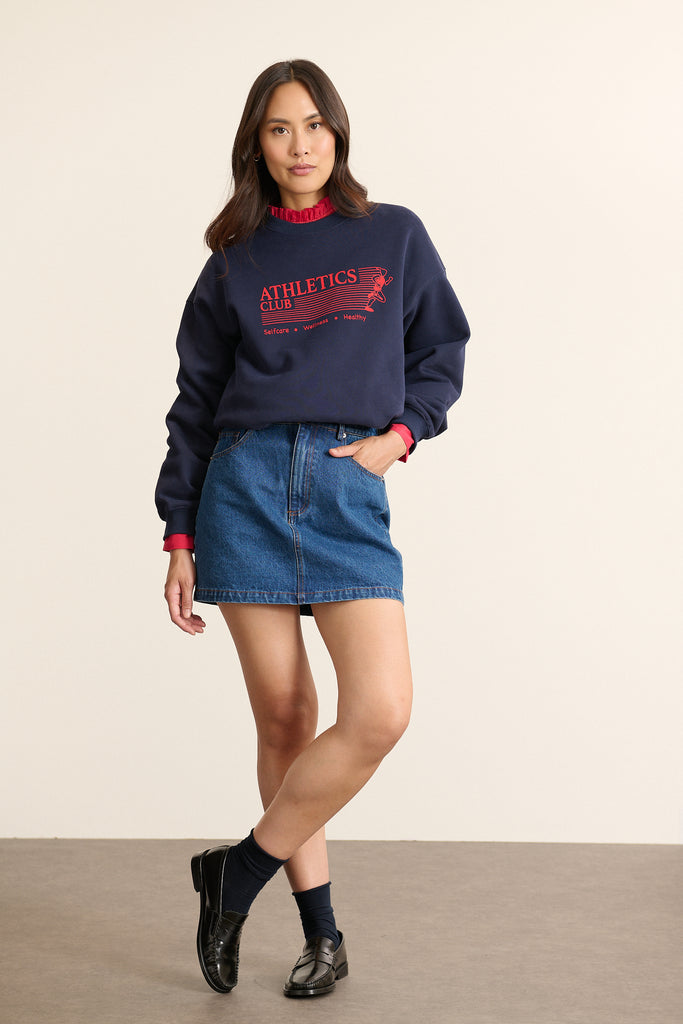 Mannequin femme de face portant un sweat ample coloris marine, col rond, manches longues et imprimé sur le devant.