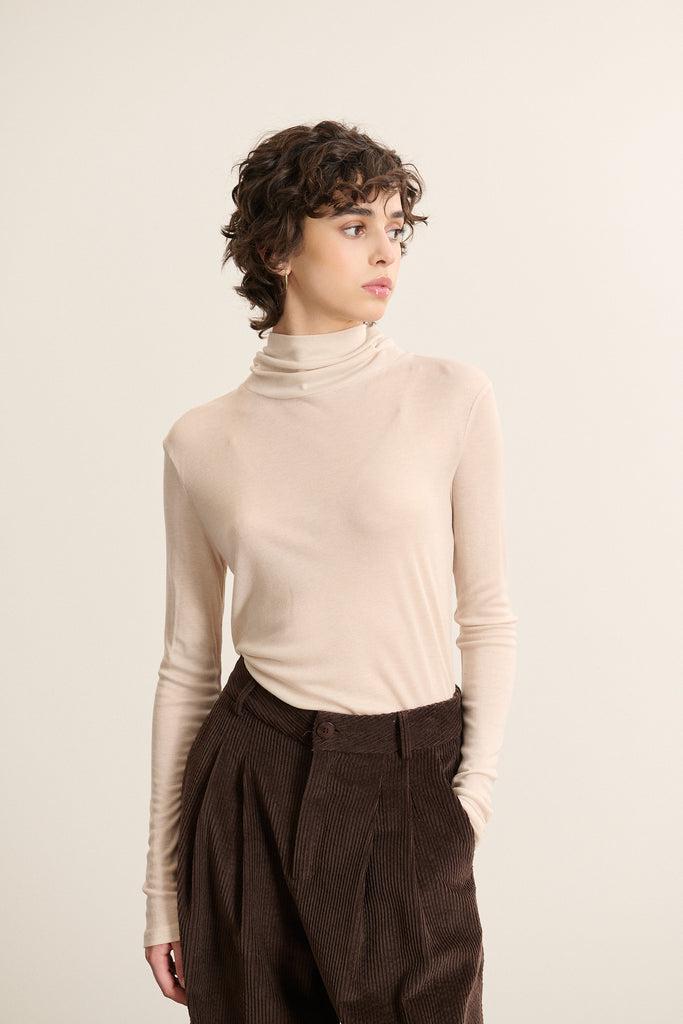 Tee-shirt aux manches longues avec tête de manche montée et coupe près du bras, finitions simples sans poignets.