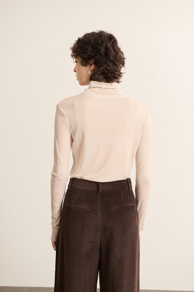 Vue arrière du sous pull à col montant coloris beige, coupe droite et ajustée avec finitions nettes en bas de la pièce.