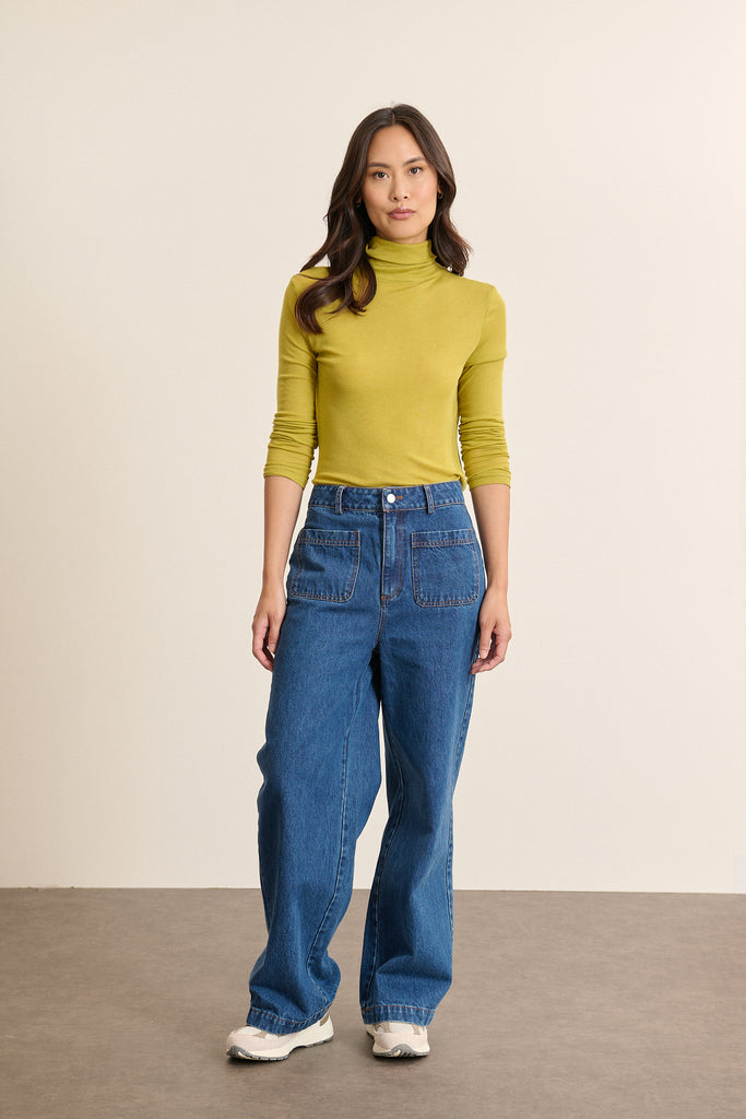 Mannequin femme de face portant un sous-pull olive à col montant, coupe ajustée et manches longues en maille fine. 