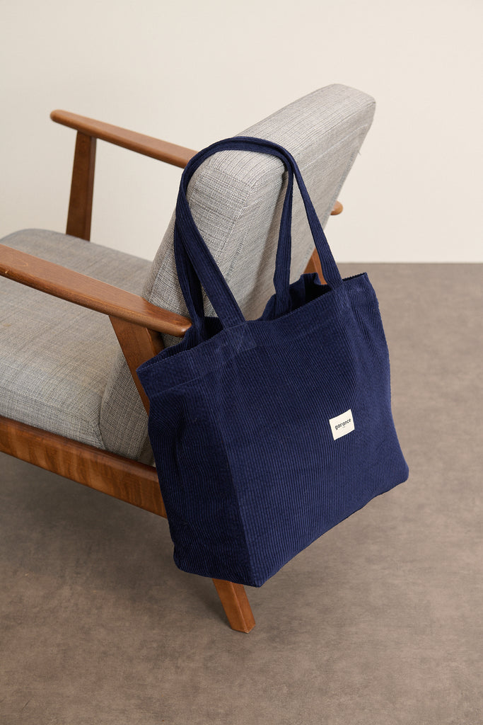 Anses larges fixées en haut du sac par surpiqûres renforcées, longueur adaptée pour un porté épaule confortable.