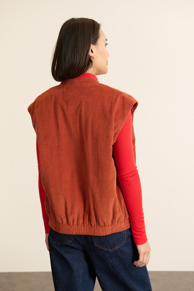 Vue arrièere de la veste sans manches en velours, matelassage uniforme et coupe droite avec emmanchures bordées. 