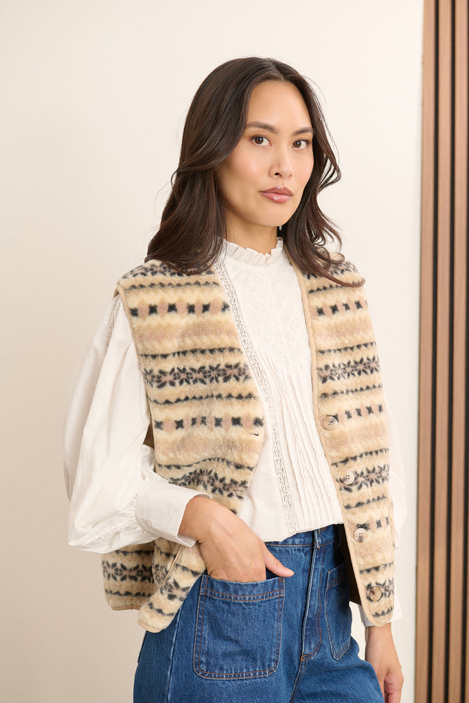 Matière effet peau de mouton 100 % polyester, imprimée beige avec motif irrégulier sur toute la surface.