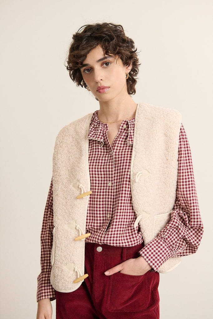 Veste sans manches écru effet peau de mouton, collection Garance automne hiver 2025, fermeture brandebourg sur le devant.