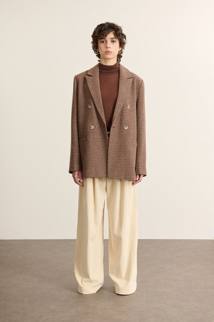 Mannequin femme de face portant une veste de tailleur croisée marron, double boutonnage et col à revers large.
